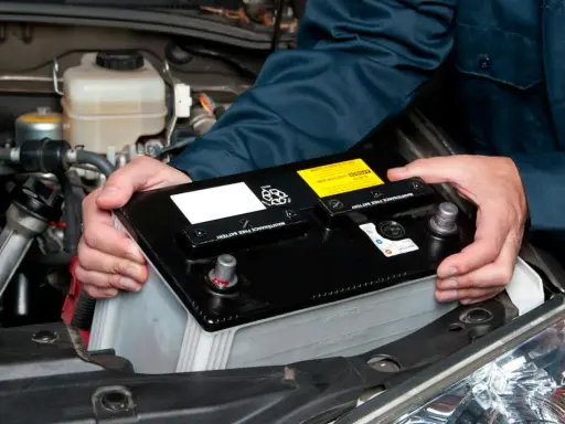 Mekaniker byter bilbatteri. Undvik kortslutning bilbatteri genom att hantera det varsamt.