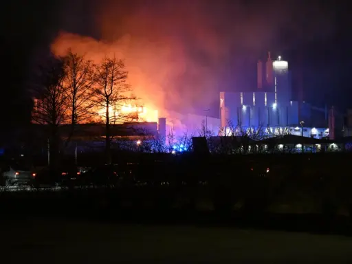 En fabrik brinner med orange och lila rök. Kanske en påminnelse om vikten av att följa kurs Boverkets brandregler för att undvika sådana katastrofer.