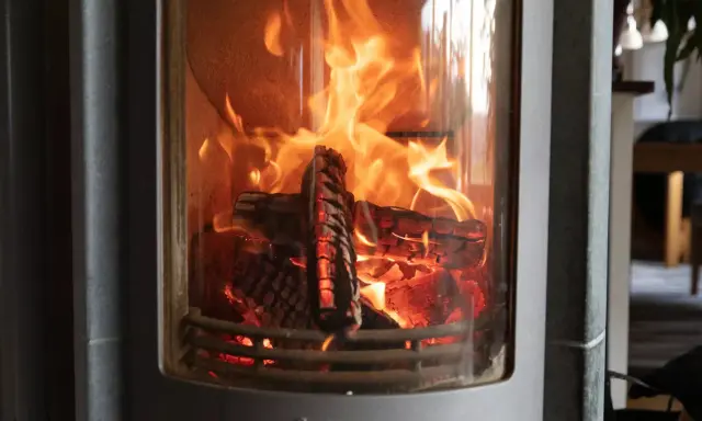 En eldstad med flammande ved. Trots det dåliga draget i kaminen lyser elden starkt och skapar en mysig atmosfär.
