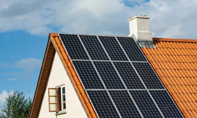 Solceller på ett tegeltak. En öppen fönsterlucka syns på husets gavel. Vissa oroar sig för solceller brandrisk.