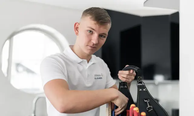 En ung elektriker från Svenska Eljouren tar fram verktyg ur sin väska för en snabb elinstallation.