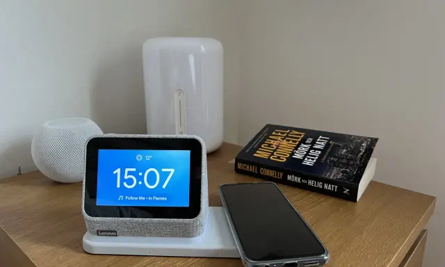 En smartklocka visar 15:07, en mobil ligger redo att ladda mobilen på natten bredvid en bok.