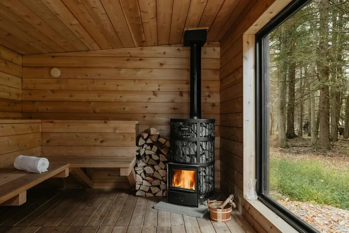 Mysig vedeldad bastu med stenar och ved. Följ brandskyddsregler för vedeldad bastu för en säker och avkopplande upplevelse i naturen.