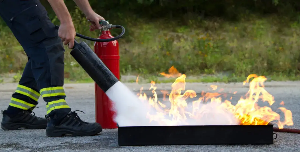 Praktisk brandutbildning på jobbet: en person släcker en eld med en brandsläckare.
