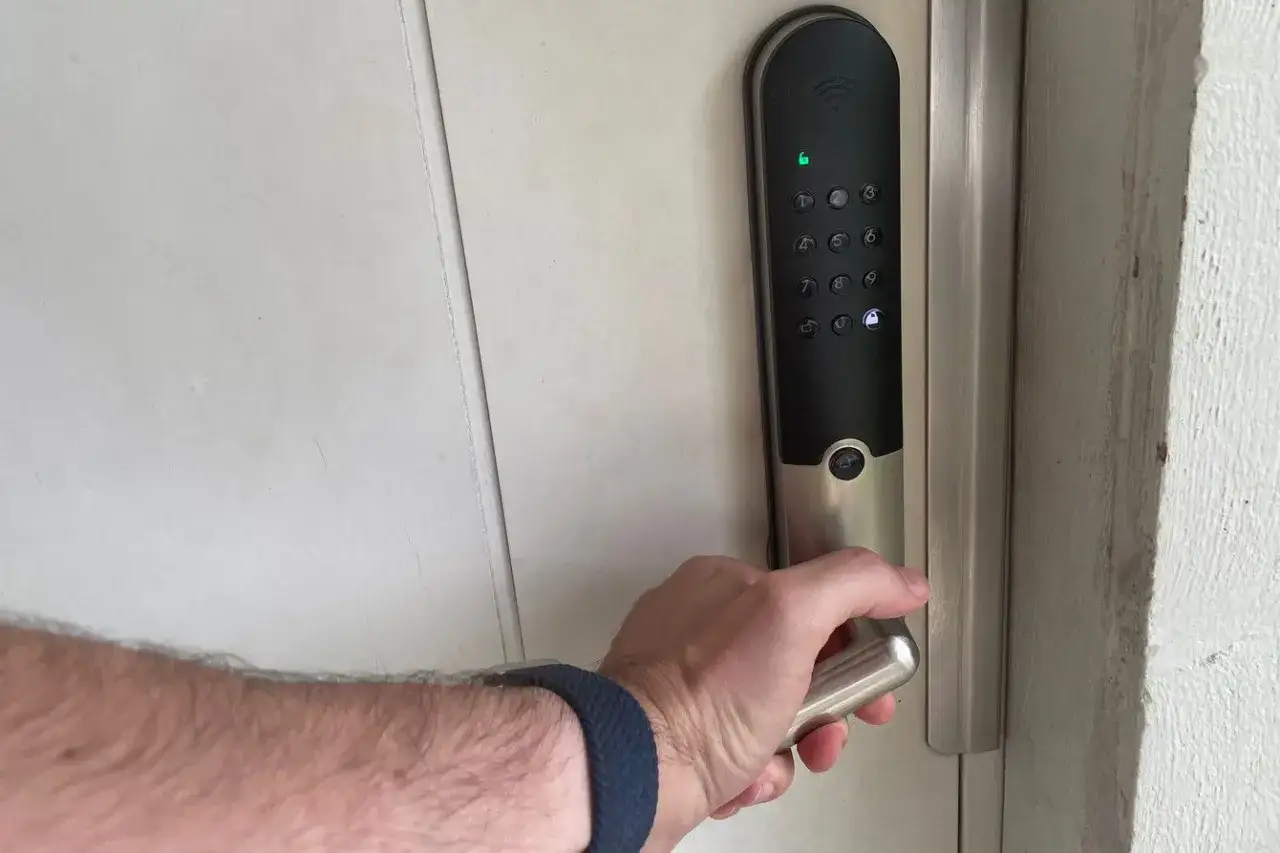 Hand griper handtaget p&aring; ett l&aring;s Yale Doorman med digital knappsats.