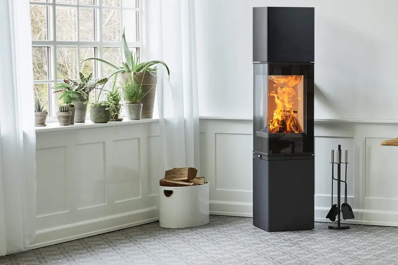 En modern kamin med flammande ved ger en mysig värme. Frågan är hur varmt det blir i en kamin när den eldas.