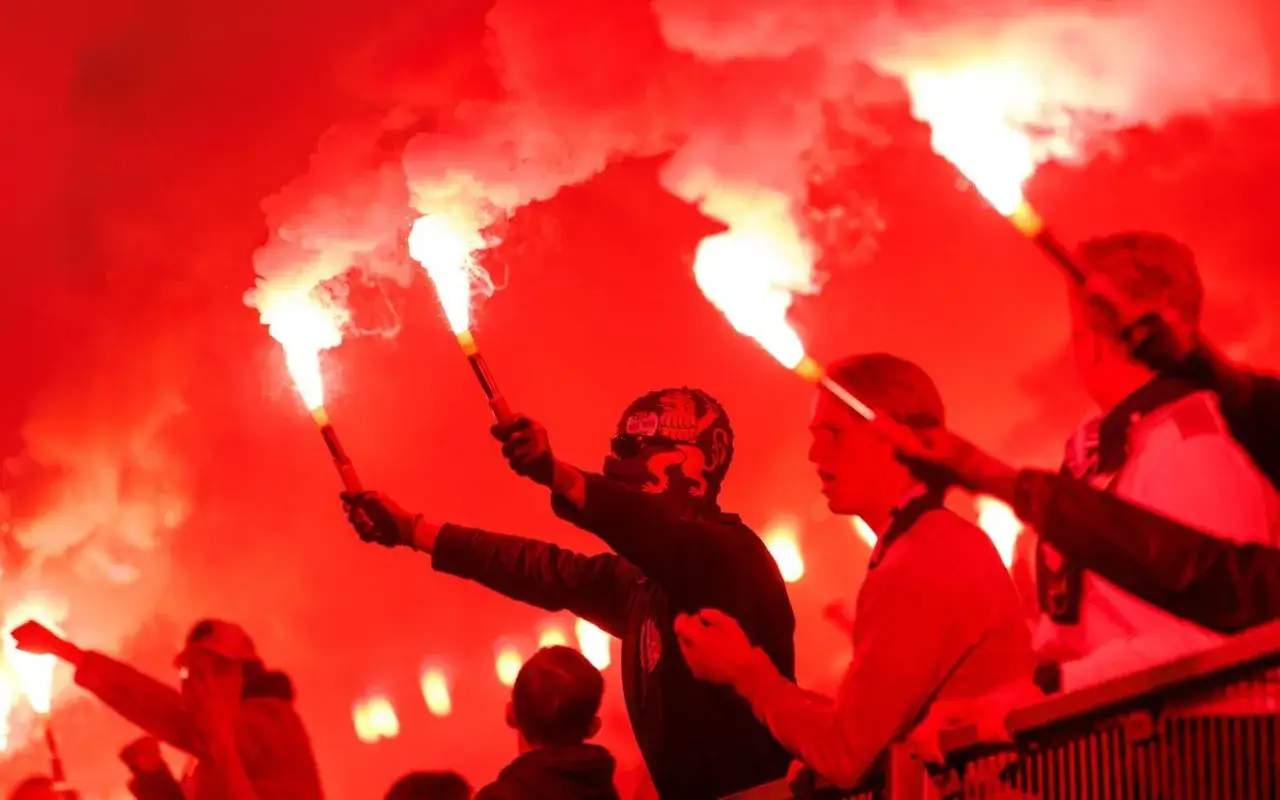 Publiken firar med facklor. En person med mask visar upp sina kunskaper inom pyroteknik.