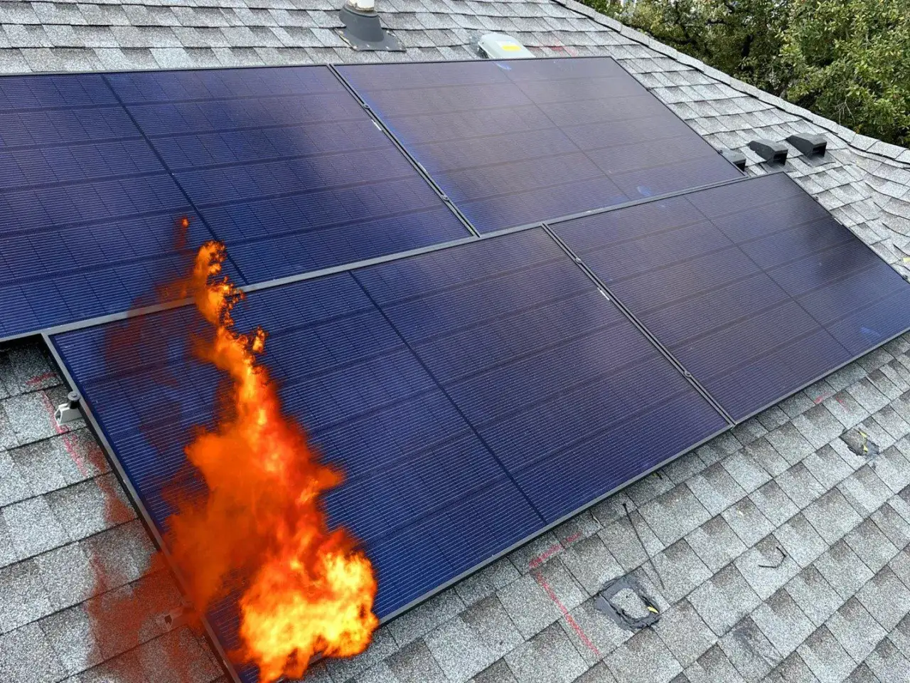 Solceller på ett tak brinner. En flammande brand sprider sig från en av panelerna, vilket visar en potentiell solceller brandrisk.