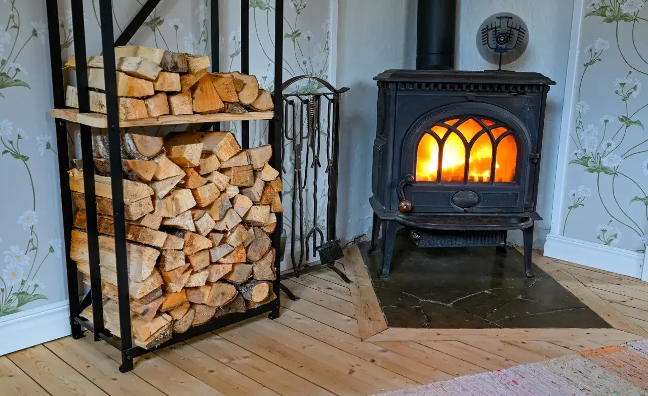 En kamin med eld i sprakar mysigt. Vedträn ligger staplade bredvid, redo att installera kamin för en varm vinter.