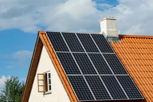 Solceller på ett tegeltak. En öppen fönsterlucka syns på husets gavel. Vissa oroar sig för solceller brandrisk.