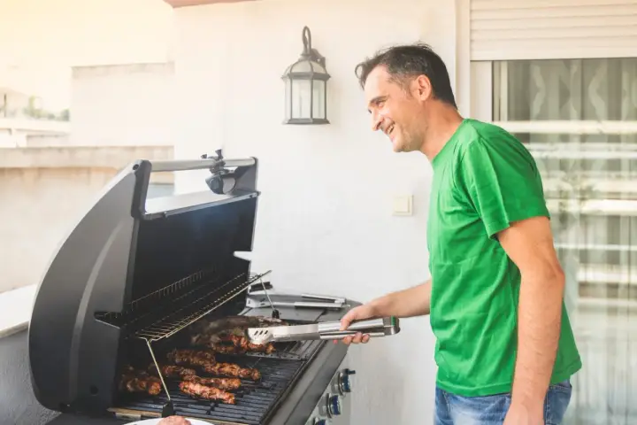 Glad man grillar korv på balkongen. Frågan "får man grilla på balkongen" är irrelevant när maten redan ligger på grillen!